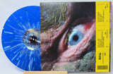 Vinyl record with a blue splatter design and a cover featuring an eye, on a white background.