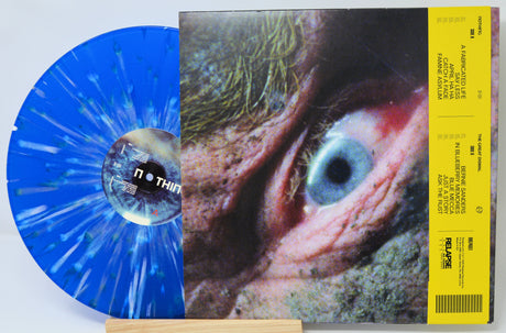 Vinyl record with a blue splatter design and a cover featuring an eye, on a white background.