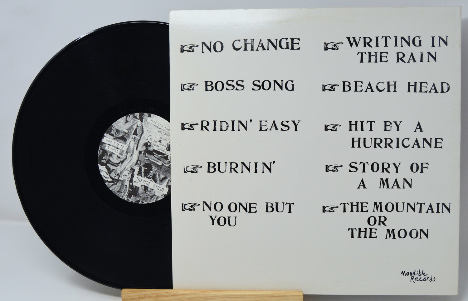 Vinyl record with white label displaying tracklist on a light gray background