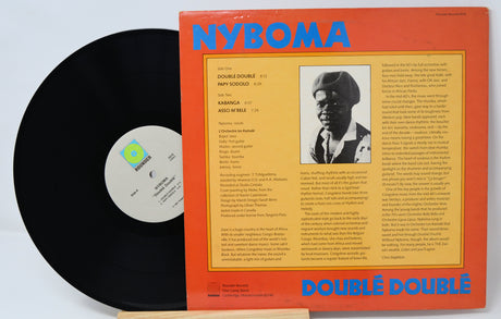 Vinyl record with orange cover featuring text and a portrait, on a light gray background