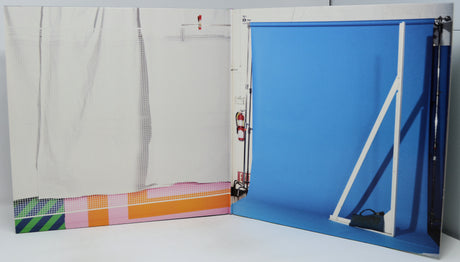 Folding screen with blue backdrop and colorful striped mat on a white floor.