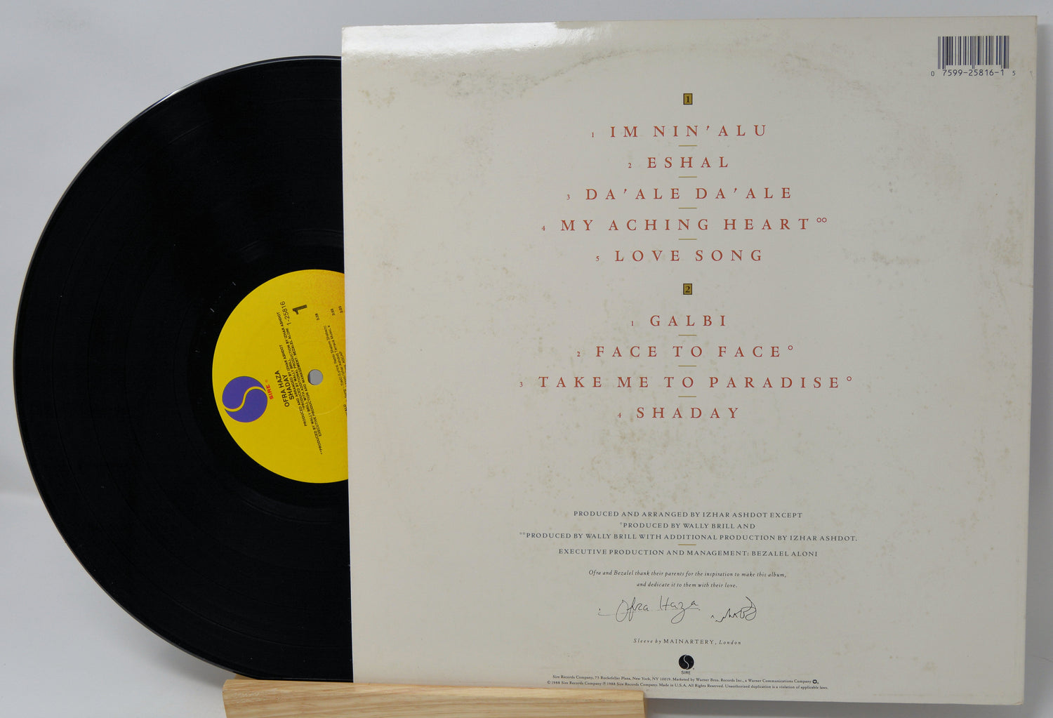 Vinyl record with a white label featuring text and a yellow label on a gray background