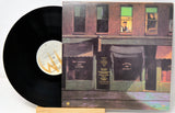 Vinyl record with a colorful album cover featuring a building facade.