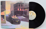 Vinyl record with cover featuring an illustration of a couple in a convertible car at sunset.
