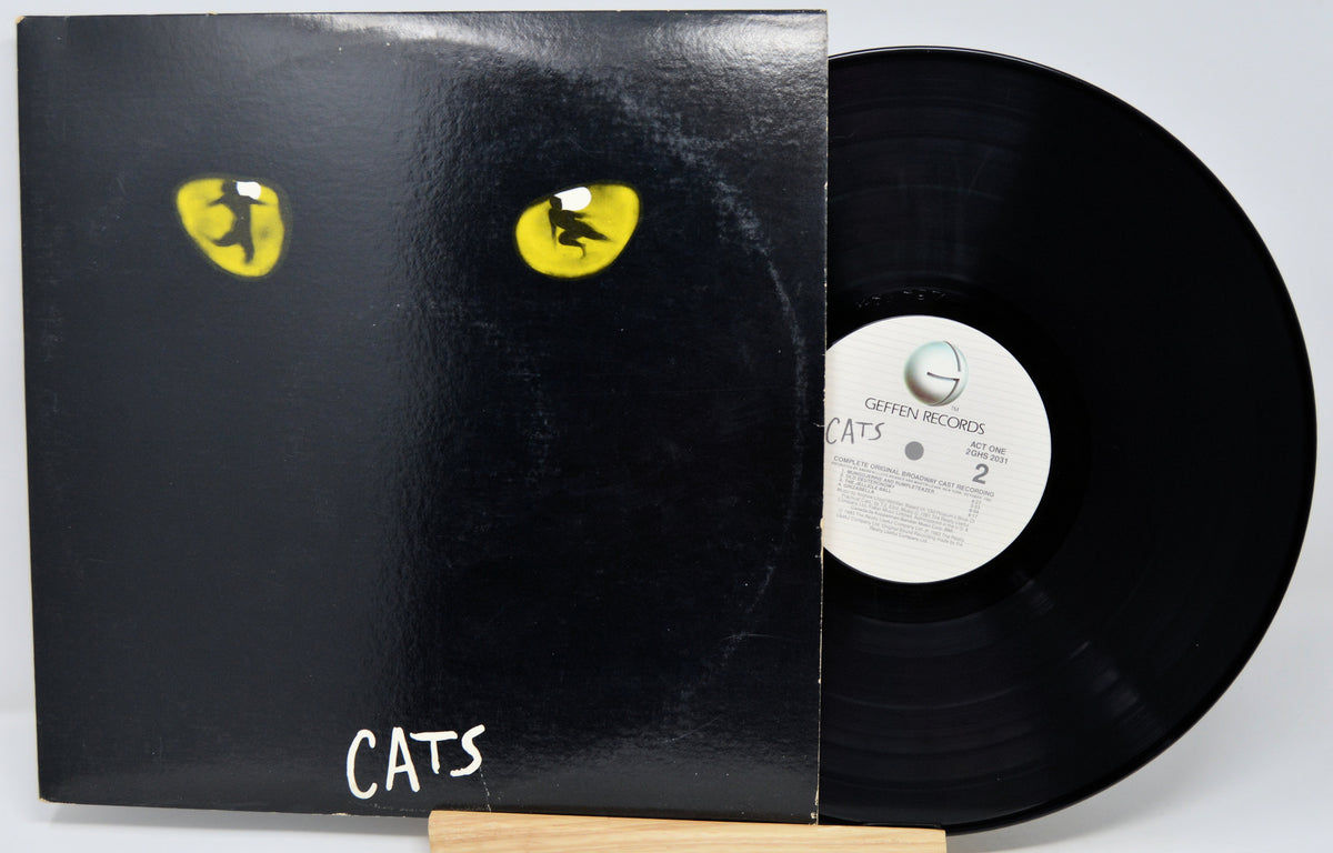 A black vinyl record partially pulled from its sleeve, featuring a black cover with two yellow cat eyes and the word 'CATS' in white near the bottom. The center label reads 'Ceffen Records' and 'Cats'.
