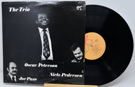 Vinyl record album 'The Trio' with the black LP partially pulled from the sleeve, showing the cover art and a yellow center label.