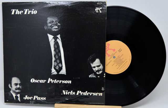 Vinyl record album 'The Trio' with the black LP partially pulled from the sleeve, showing the cover art and a yellow center label.