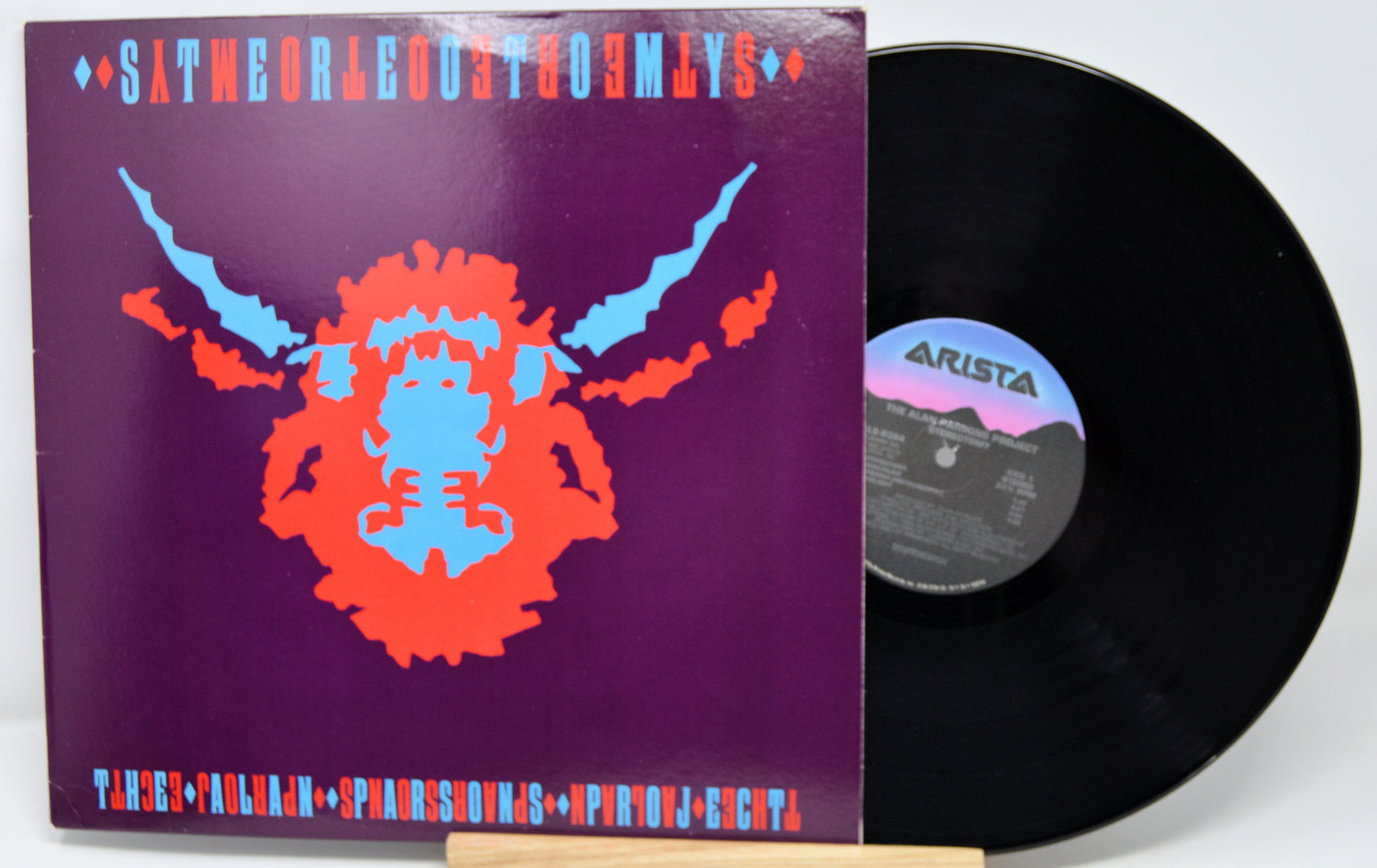 Vinyl record with a colorful cover featuring a face design on a purple background.