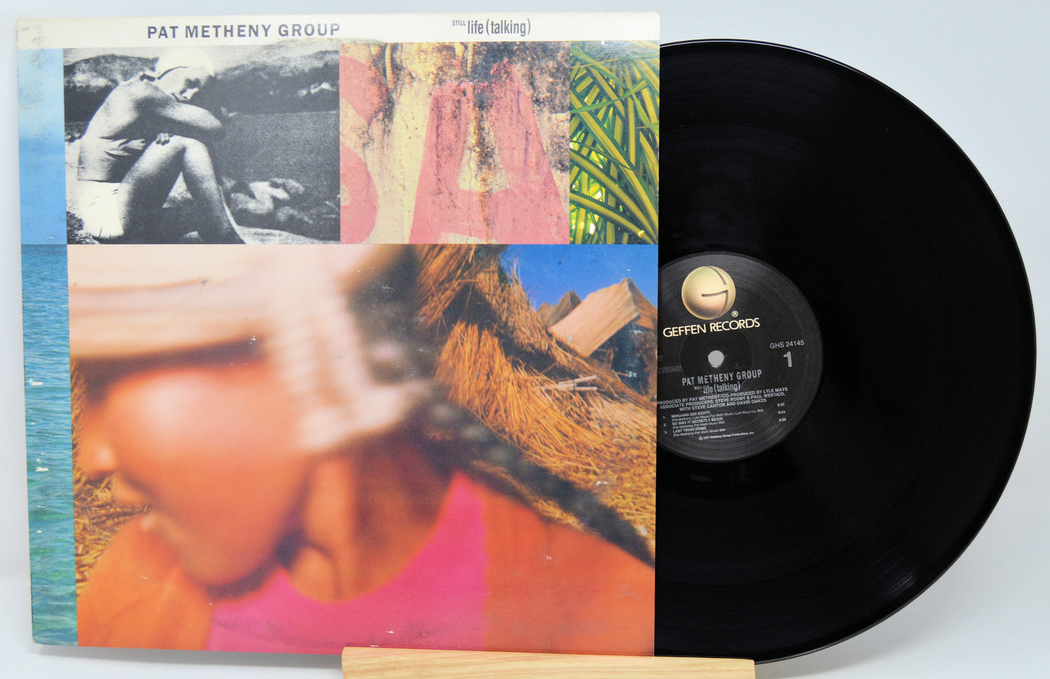 Vinyl record with cover featuring a person and scenic images, on a light blue background.