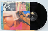 Vinyl record with cover featuring a person and scenic images, on a light blue background.