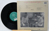 Vinyl record with cover featuring a black and white photo of people and text.