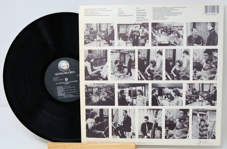 Vinyl record with a black label and a cover featuring black and white photos of people.