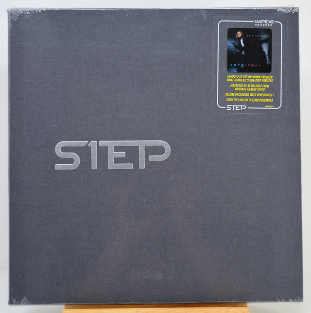 A square dark gray album or book-style package with large embossed 'STEP' lettering and a small 'IMPEX' sticker in the top-right corner, photographed against a plain light background.