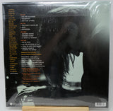 The back cover of a vinyl record album in its shrink wrap, featuring a large black-and-white silhouette of a woman's profile with the tracklist printed in yellow and orange text on a dark background.