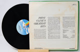 A vintage vinyl record partially pulled from its open sleeve, showing the black record on the left and the cream-colored inner sleeve with printed text on the right. The sleeve has a green edge and shows the title 'Patsy Cline's Greatest Hits.