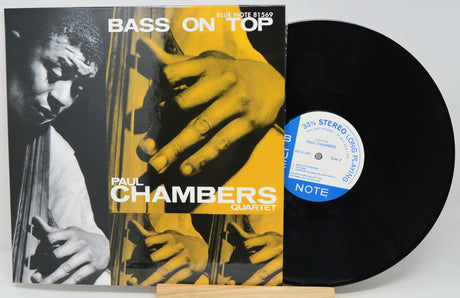 Vinyl record album for Paul Chambers Quartet's 'Bass on Top' with the LP partially pulled from the jacket, showing the black record, blue-and-white center label, and album cover artwork.