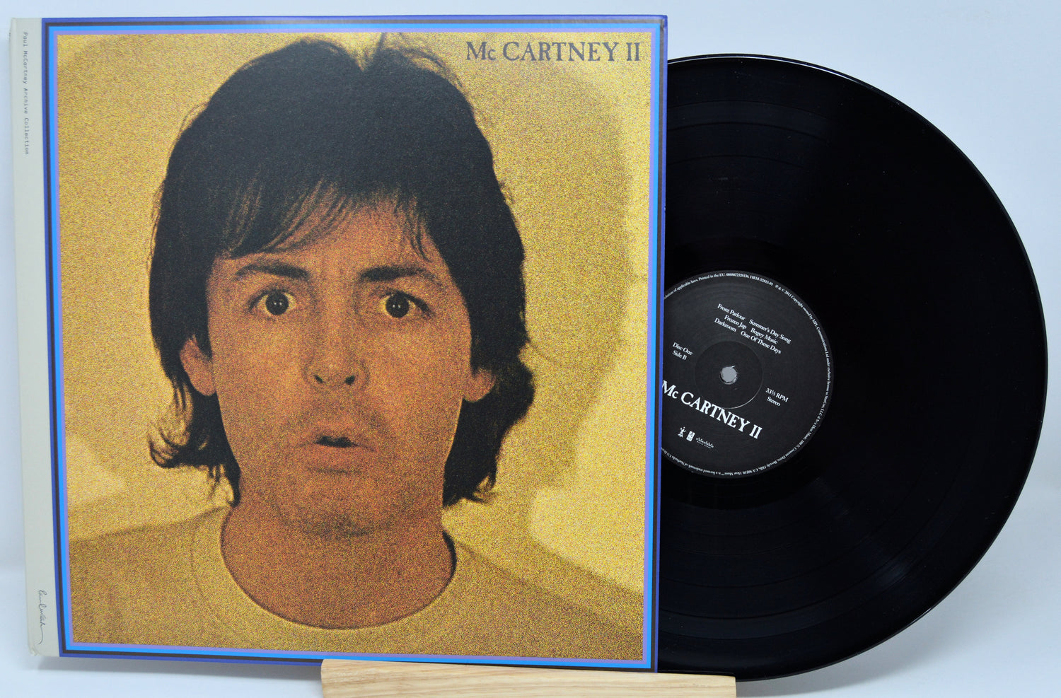 McCartney II vinyl record album with the illustrated cover jacket in front and the black LP record partially visible behind it on a light background.