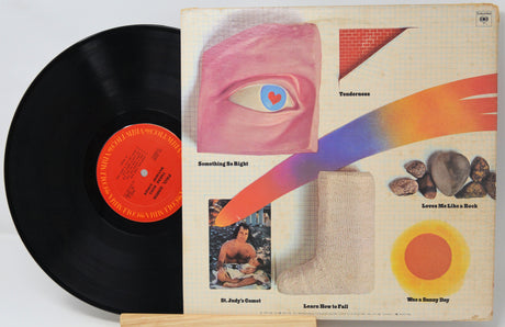 Vinyl record with colorful album cover featuring abstract designs and text.