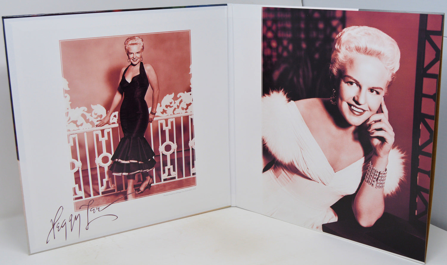 An open photo album or book showing two vintage portraits of a blonde woman. The left page has a sepia-toned portrait of her standing by a railing, with a signature at the bottom.