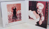 An open photo album or book showing two vintage portraits of a blonde woman. The left page has a sepia-toned portrait of her standing by a railing, with a signature at the bottom.