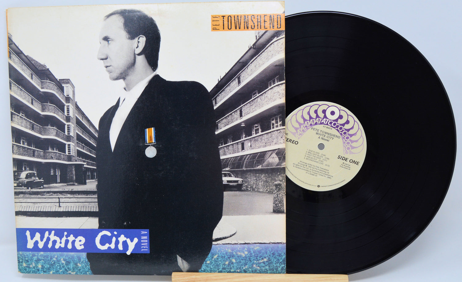 Vinyl record with cover featuring a person in a suit and 'White City' text, on a light blue background.