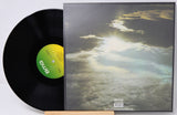 A black vinyl record partially pulled from its sleeve, showing the album cover artwork of clouds with bright sunlight breaking through. The center label and bottom right of the sleeve both show the BMS logo.