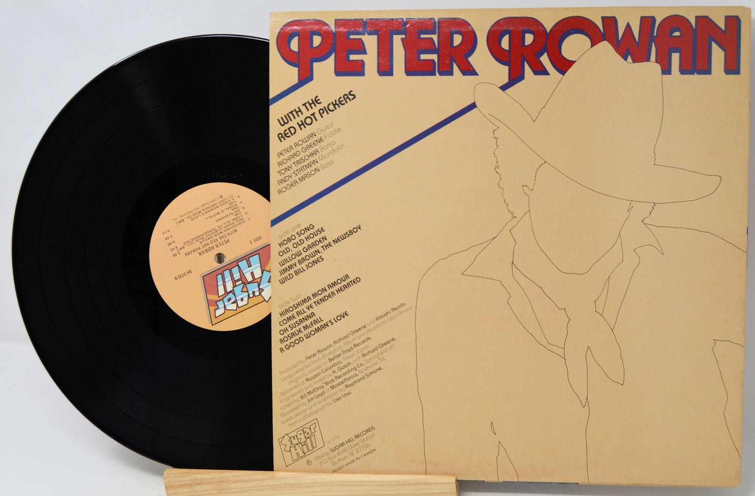 Peter Rowan 'With Me And The Red Hot Peppers' vinyl record LP, showing the black record partially pulled from its tan cardboard sleeve with red and blue title text.