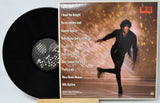 Vinyl record with yellow label featuring a photo of a person playing guitar and text.