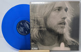 Blue vinyl record and its cover featuring a portrait of a person.