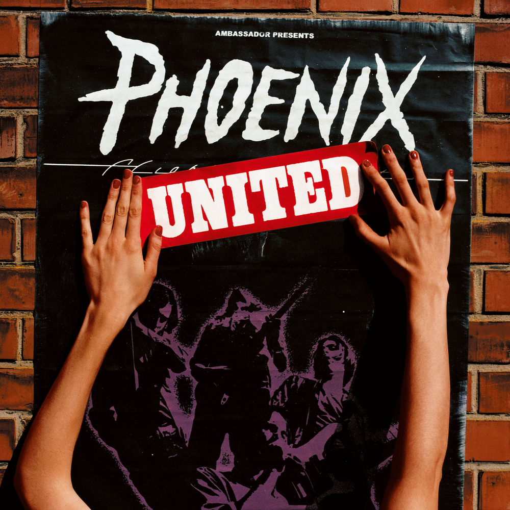 Person holding a 'Phoenix United' poster against a brick wall