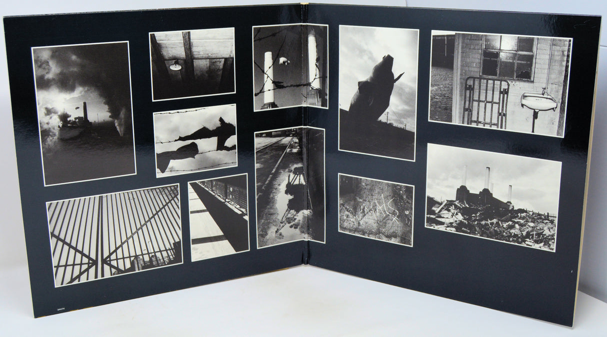 An open black photo album or book spread, displaying multiple black-and-white photographic prints arranged in a collage layout on the interior pages.