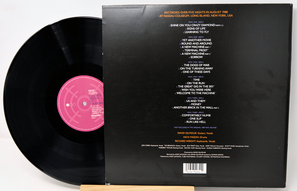 Vinyl record with pink label and back cover displaying tracklist on a white background