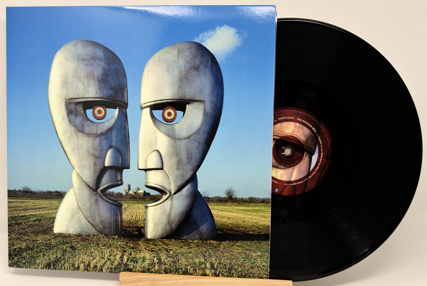 Pink Floyd's 'The Wall' vinyl record LP with its illustrated cover jacket leaning against a light beige background, with the black record partially pulled out and showing the center label.