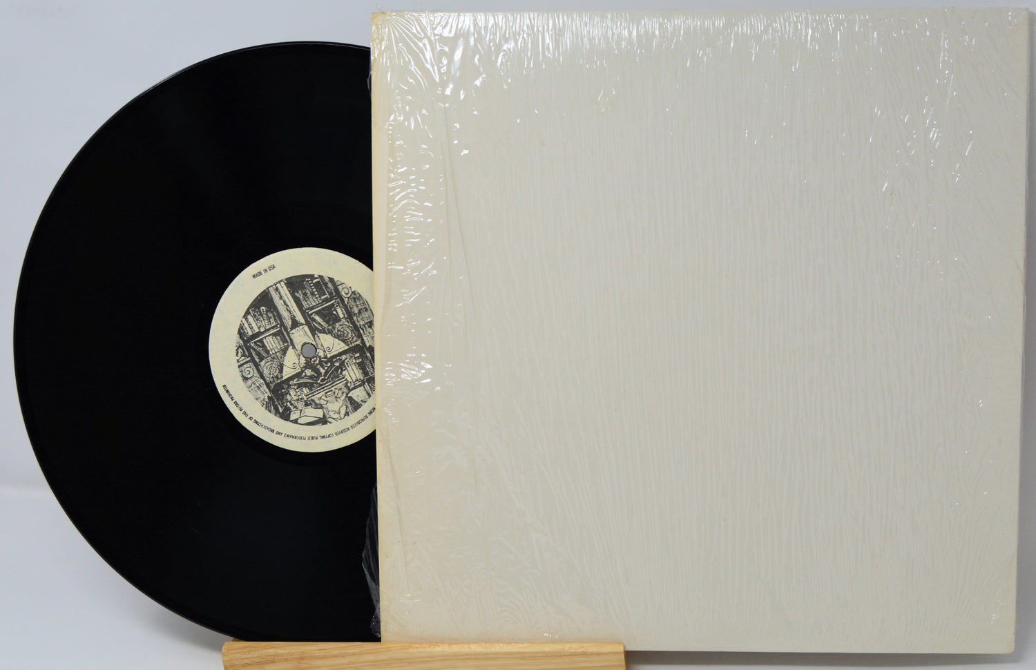 Vinyl record with a white cover on a gray background