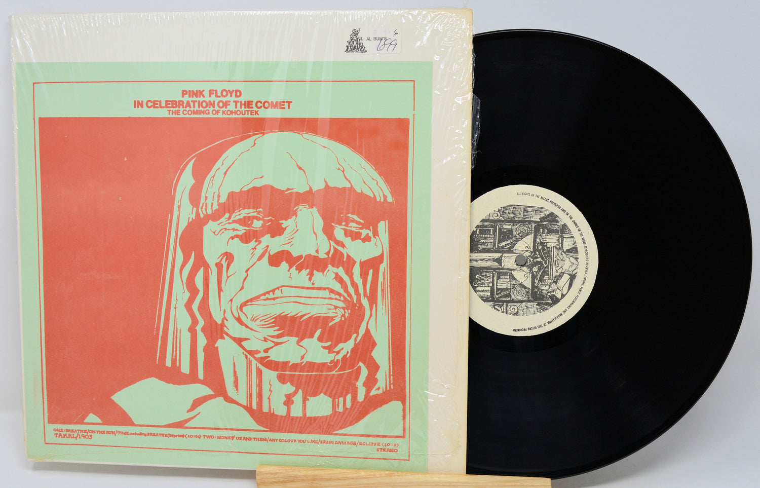 Vinyl record with a cover featuring a stylized face design on a red background.