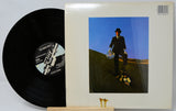 Vinyl record with a cover featuring a person in a suit on a hillside.