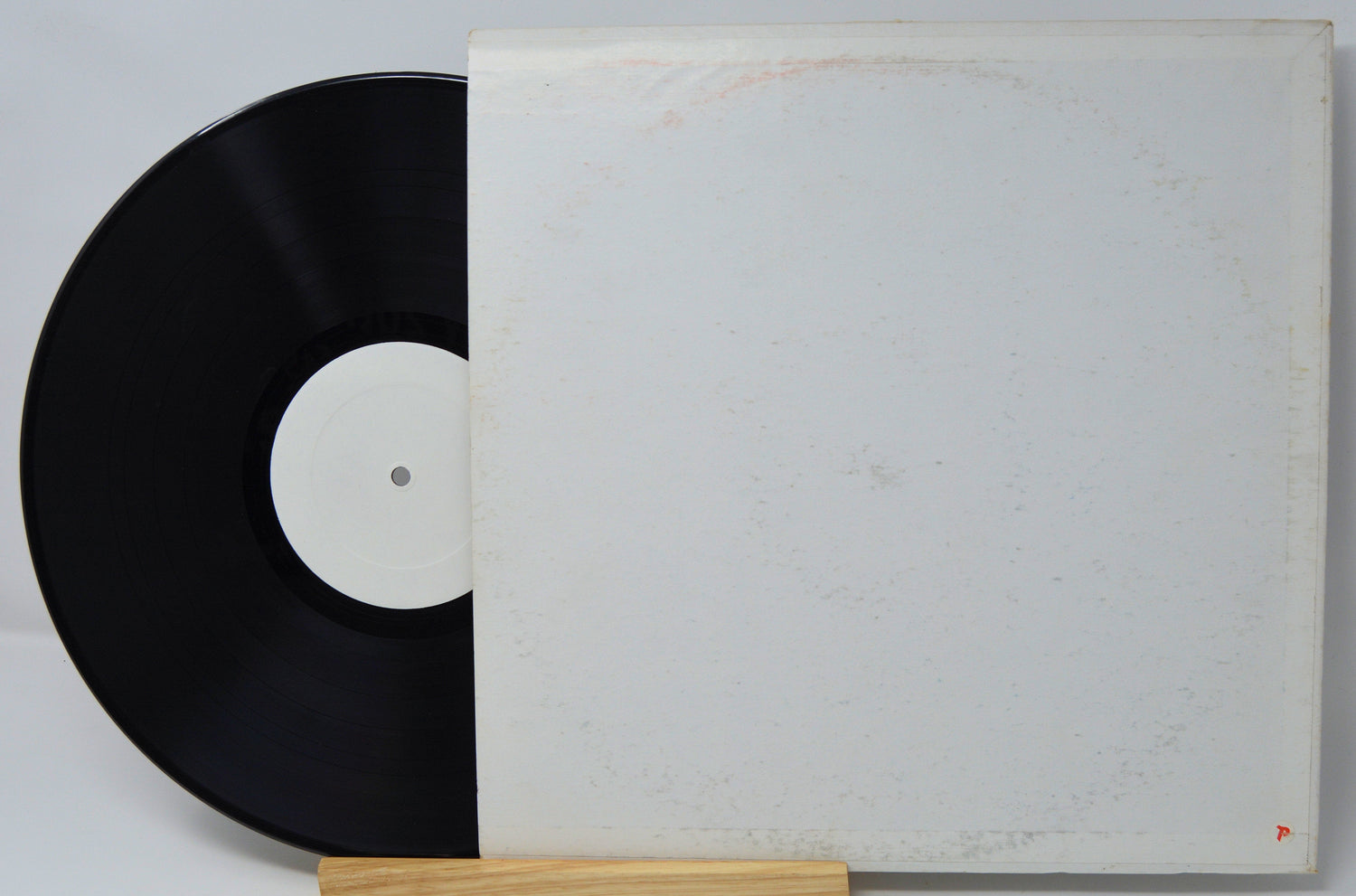 Vintage vinyl record with blank white label and plain white sleeve, partially shown.