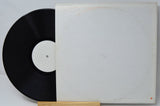 Vintage vinyl record with blank white label and plain white sleeve, partially shown.