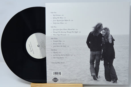 Vinyl record LP shown with the back cover insert, featuring a black record partially covering the sleeve and a printed tracklist and couple photograph on the cover.