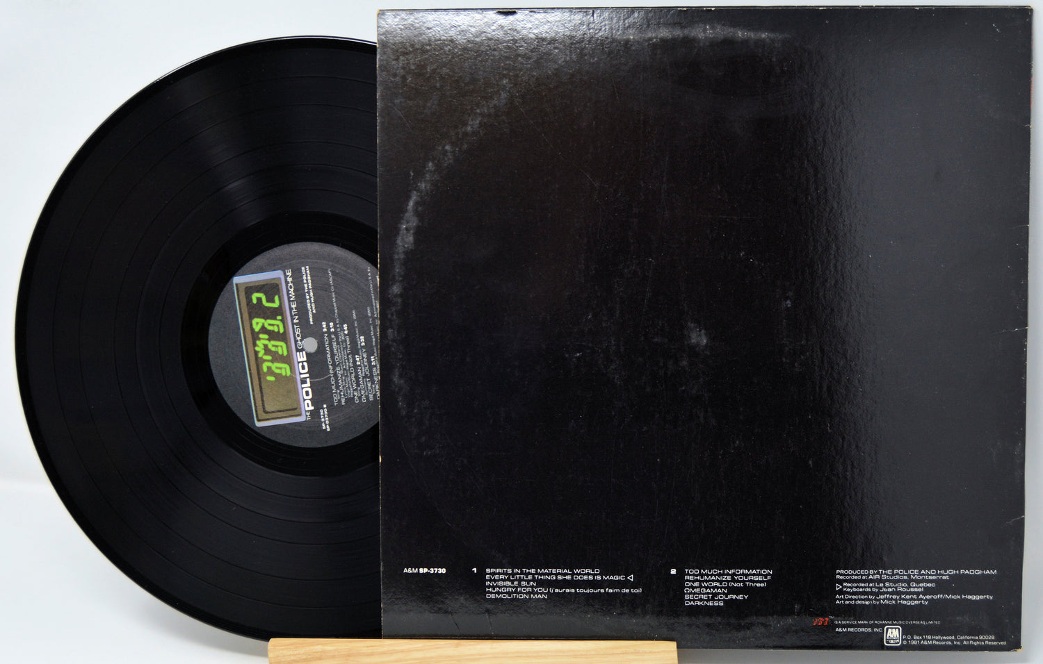 Black vinyl record with a visible label and matching black record cover on a white background
