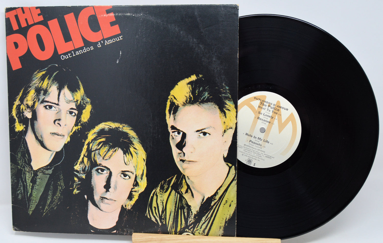 Vinyl record and cover of 'The Police' album 'Outlandos d'Amour' on a light gray background