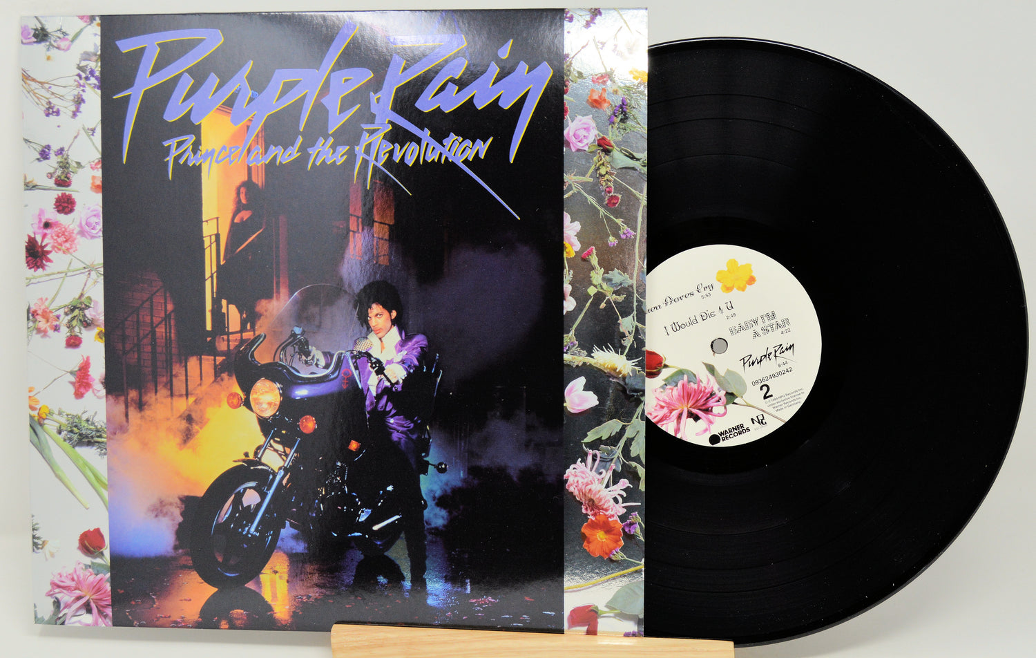 Vinyl record and cover for 'Purple Rain' by Prince and the Revolution on a white background.