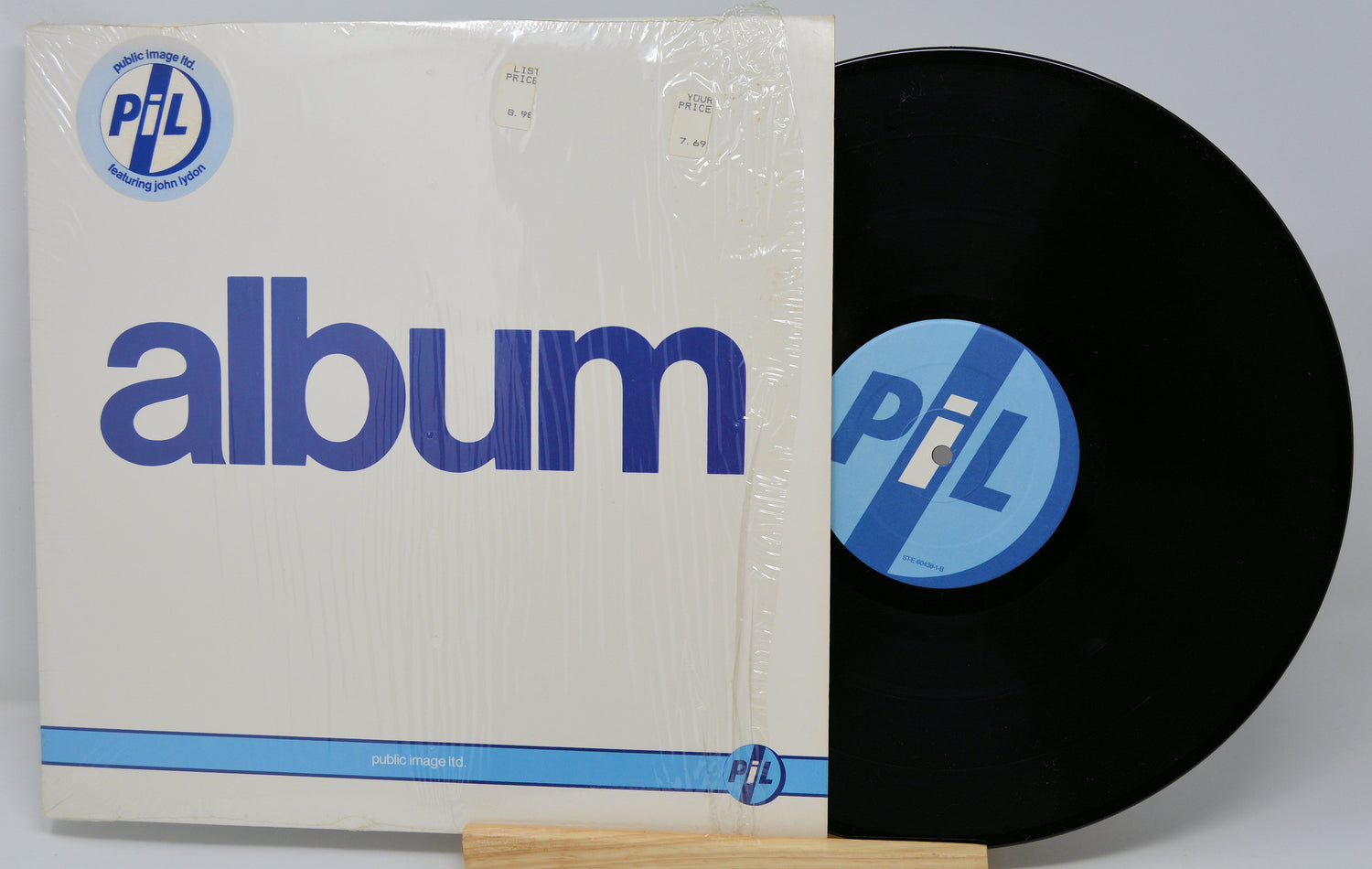 Vinyl record with cover featuring 'PIL' logo on a white background