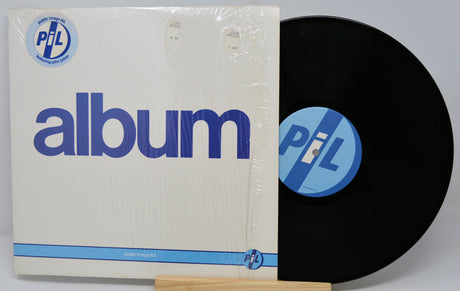 Vinyl record with cover featuring 'PIL' logo on a white background