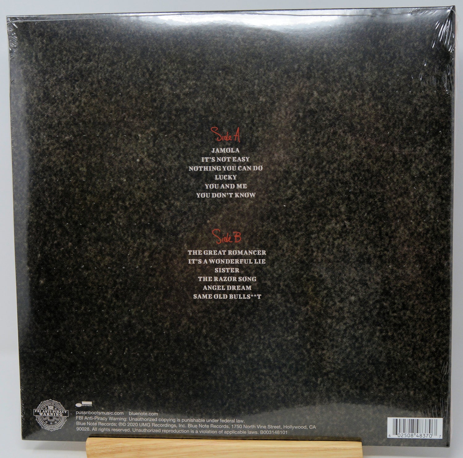 The back cover of a vinyl record album in shrink wrap, showing track listings for Samh A and Samh B in red and white text over a dark textured background.