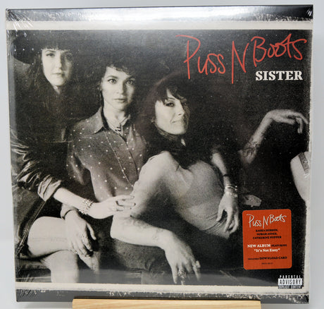 Puss N Boots - Sister vinyl record album cover, showing a black and white photo of three women with red and white title text, plus an orange sticker on the lower right.