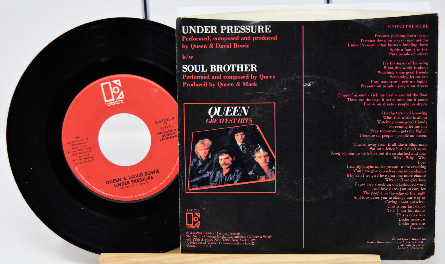 Vinyl record with red label and black cover featuring Queen on a white background