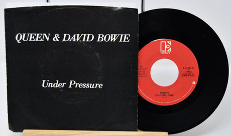 Vinyl record and cover for 'Under Pressure' by Queen and David Bowie on a white background