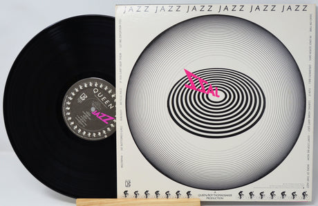 A vinyl record and its album cover for Queen's 'Jazz' album, displayed on a light wood stand against a white background.