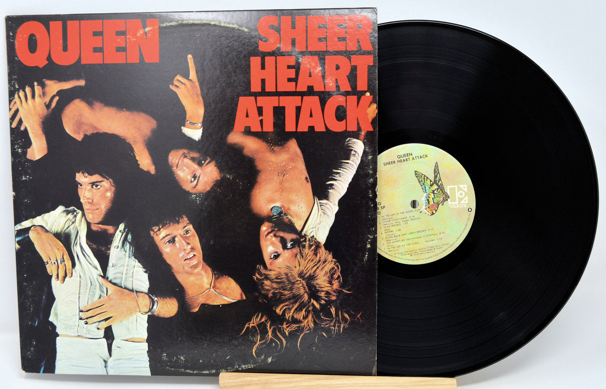 Queen's 'Sheer Heart Attack' vinyl LP album with the cover standing beside the black record on a small wooden stand against a white background.